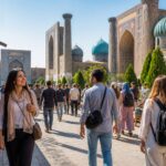 Grupo de pessoas caminhando em uma rua movimentada de cidade no Uzbequistão, com arquitetura tradicional e moderna ao fundo.