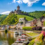 Vista da cidade de Cochem na Alemanha com o castelo Reichsburg no topo da colina, o rio Mosela e casas tradicionais ao redor.