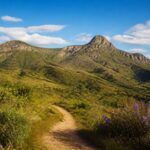Paisagem natural das colinas verdes e montanhas de Serro, Minas Gerais, com céu azul e vegetação abundante.